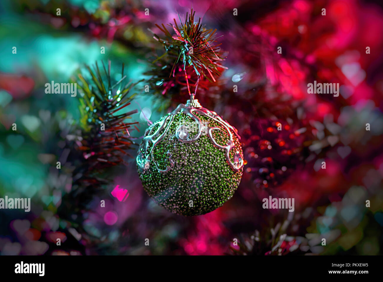 Lucido verde decorazione palle di Natale in colore viola-rosso fumo, su di un albero di Natale sfondo. Concetto di una moderna scheda di Natale. Foto Stock