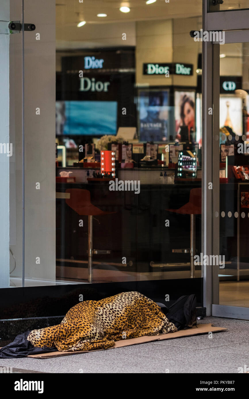 La persona senza dimora con pelle di leopardo coperchio in negozio porta, Oxford Street, London, England, Regno Unito Foto Stock