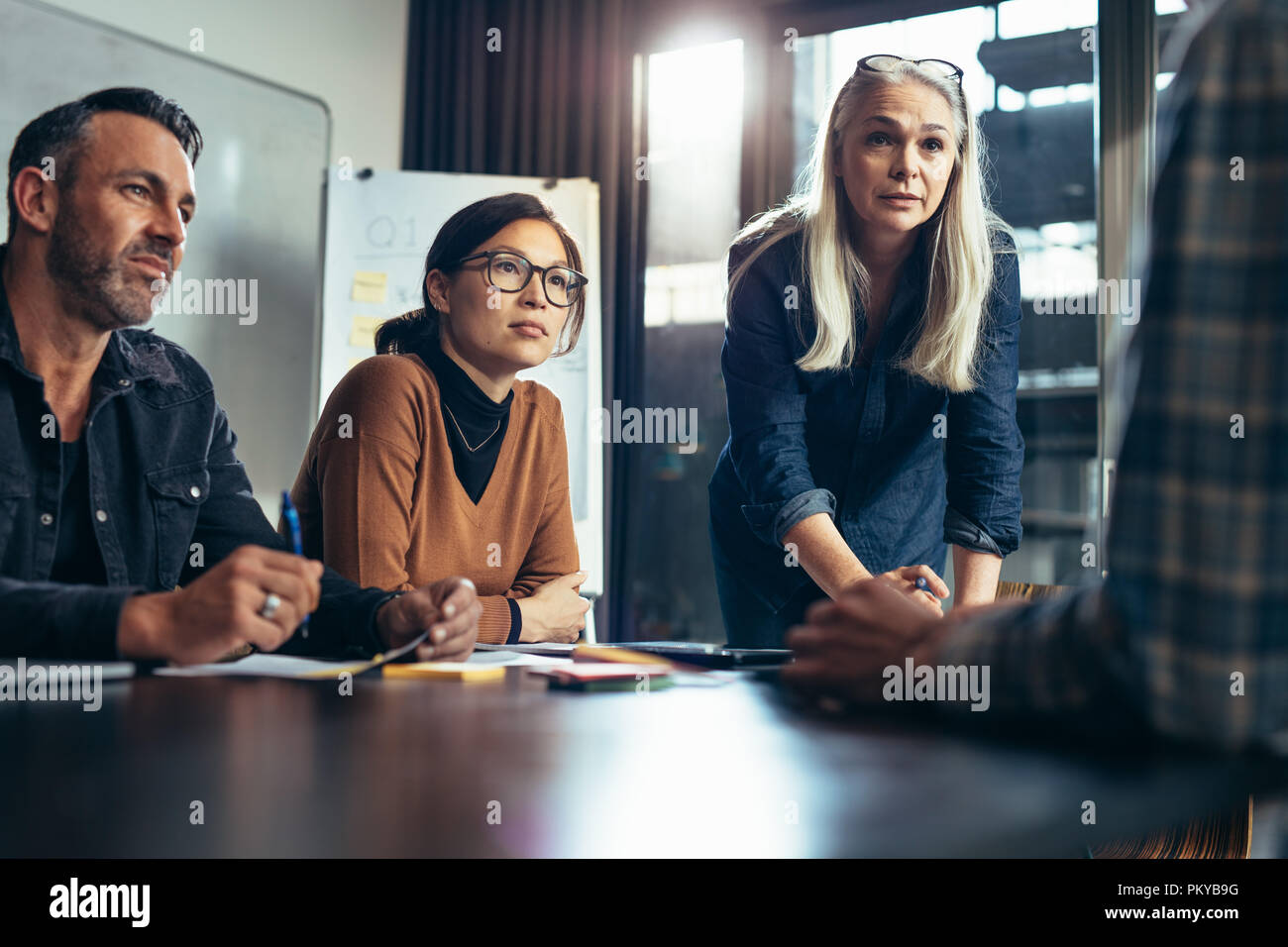 Un gruppo di uomini di affari che ascoltare le idee del giovane collega in sala riunioni. Diversi team di business il brainstorming in sala riunioni. Foto Stock