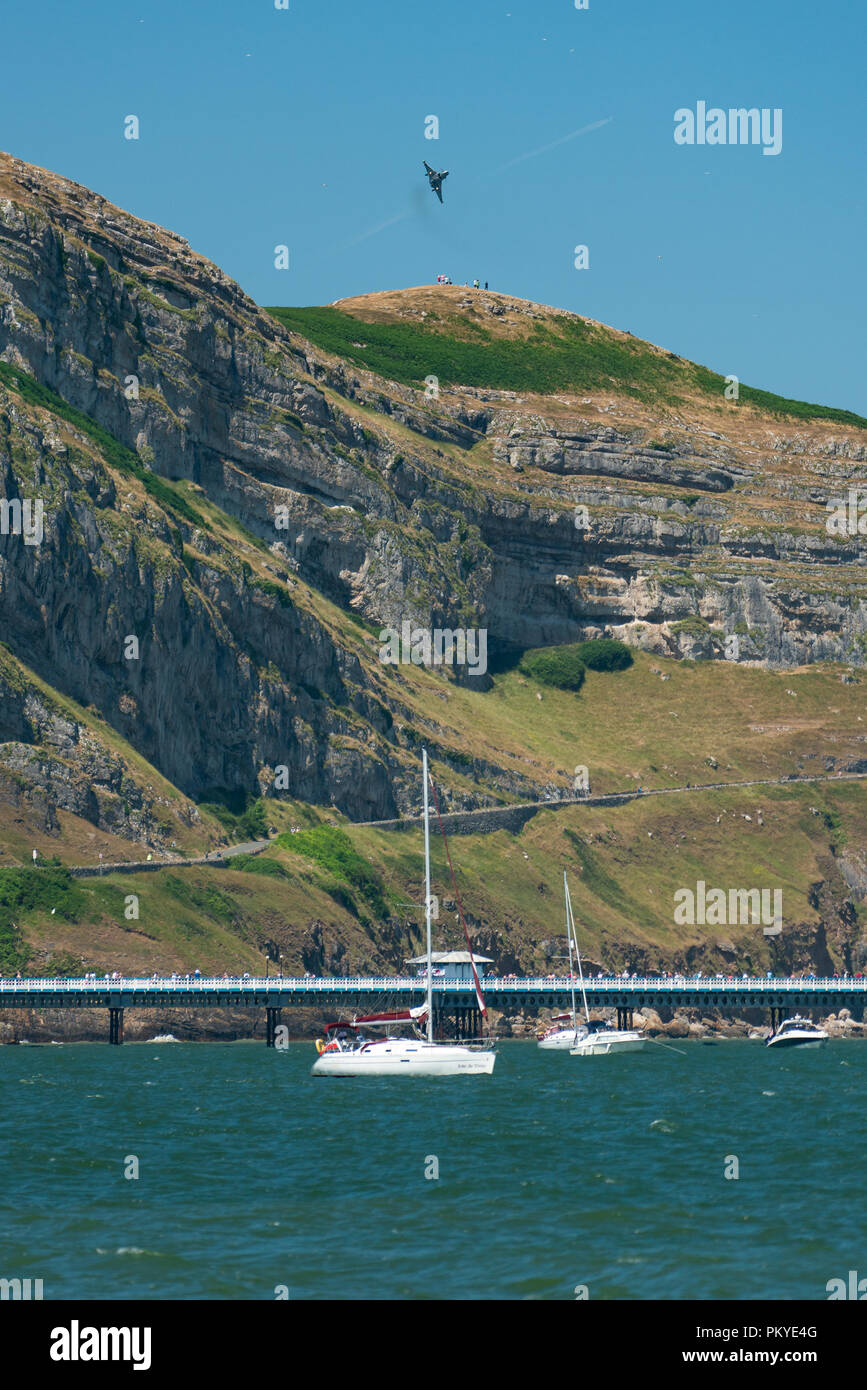 Un gruppo di spettatori in piedi sul Great Orme di ottenere una vista ravvicinata di un RAF Eurofighter Typhoon facendo passare lento con il carro verso il basso su Abilitato Foto Stock