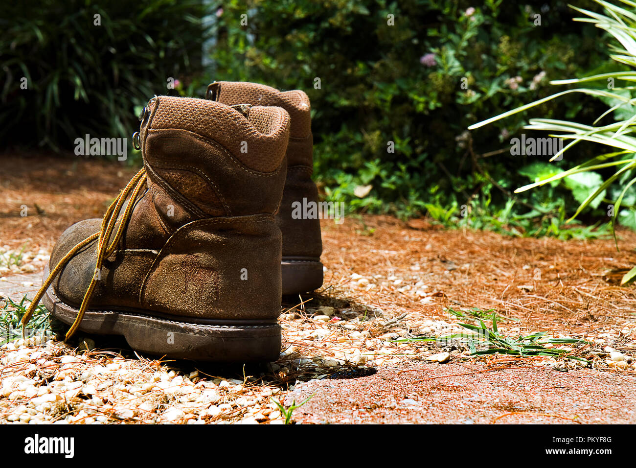 Fine della giornata concetto con uomini usurato e weathered stivali da lavoro off all'esterno. Foto Stock