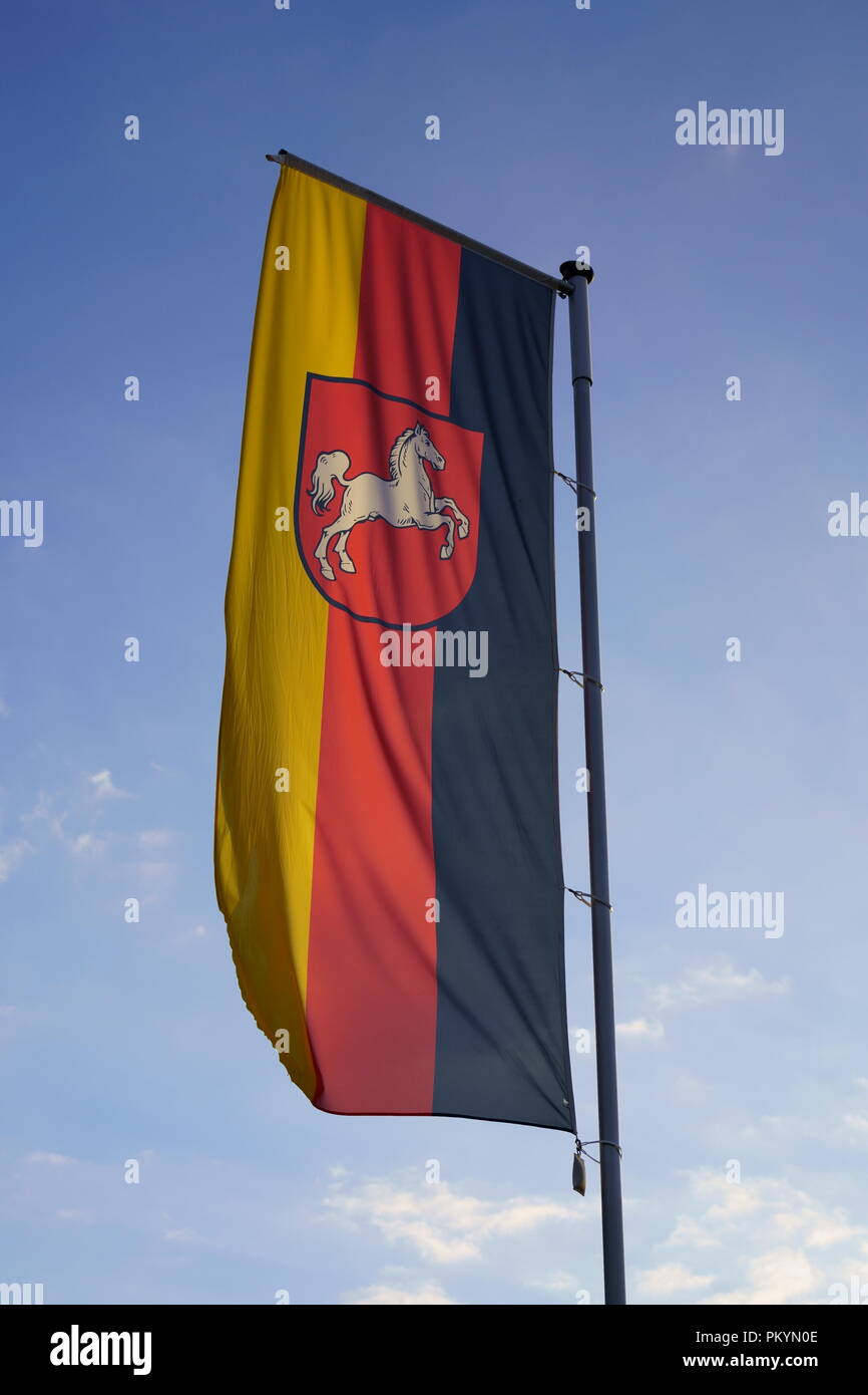 Indicatore di stato della Bassa Sassonia in Germania. Lo stato tedesco bandiera contro il cielo blu sullo sfondo. Foto Stock