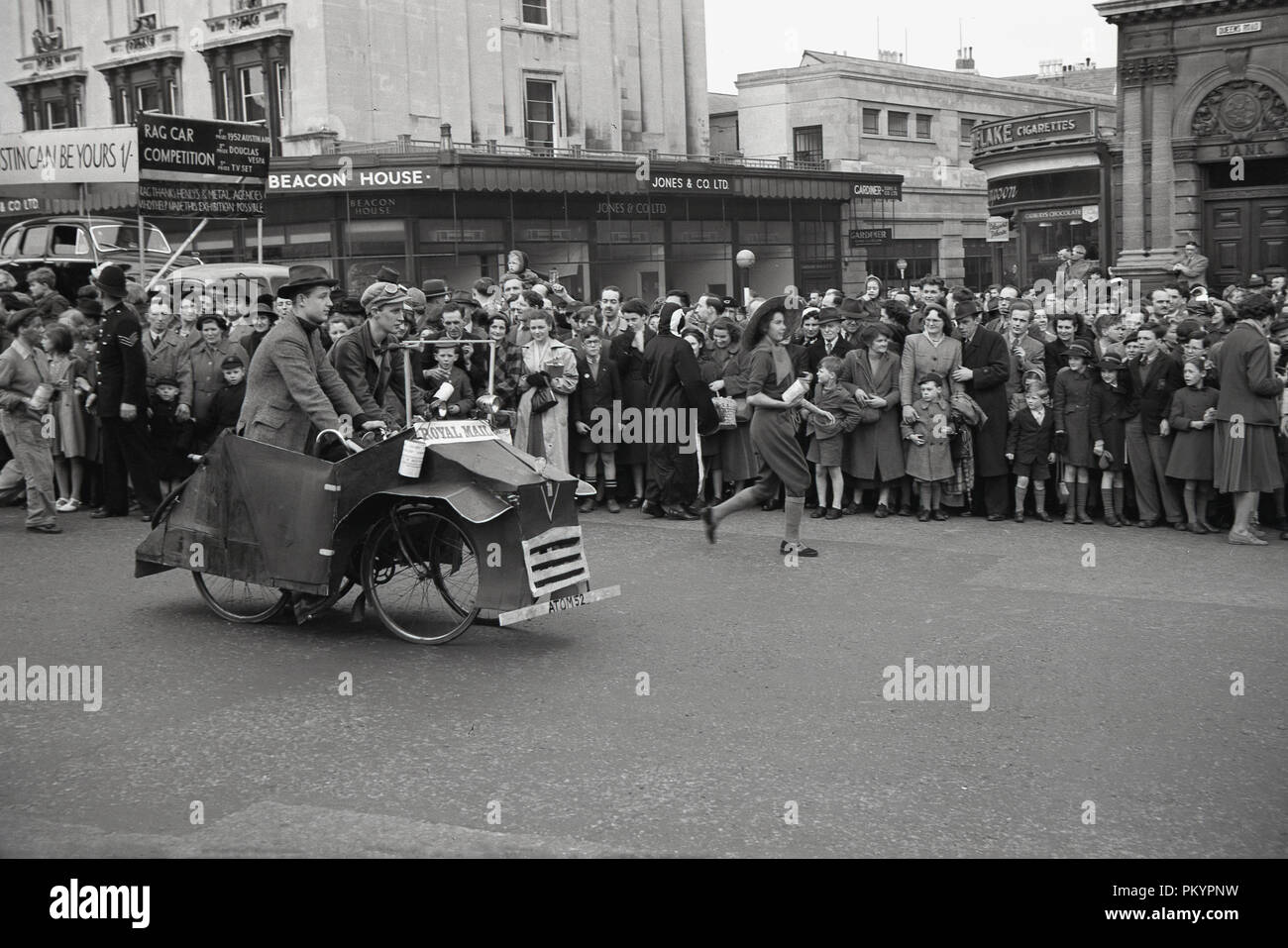 Degli anni Cinquanta, storici, gli studenti universitari in costumi e su veicoli silly prendendo parte in processione ragweek o la street parade, guardato da spettatori, Bristol, Inghilterra, Regno Unito. Foto Stock