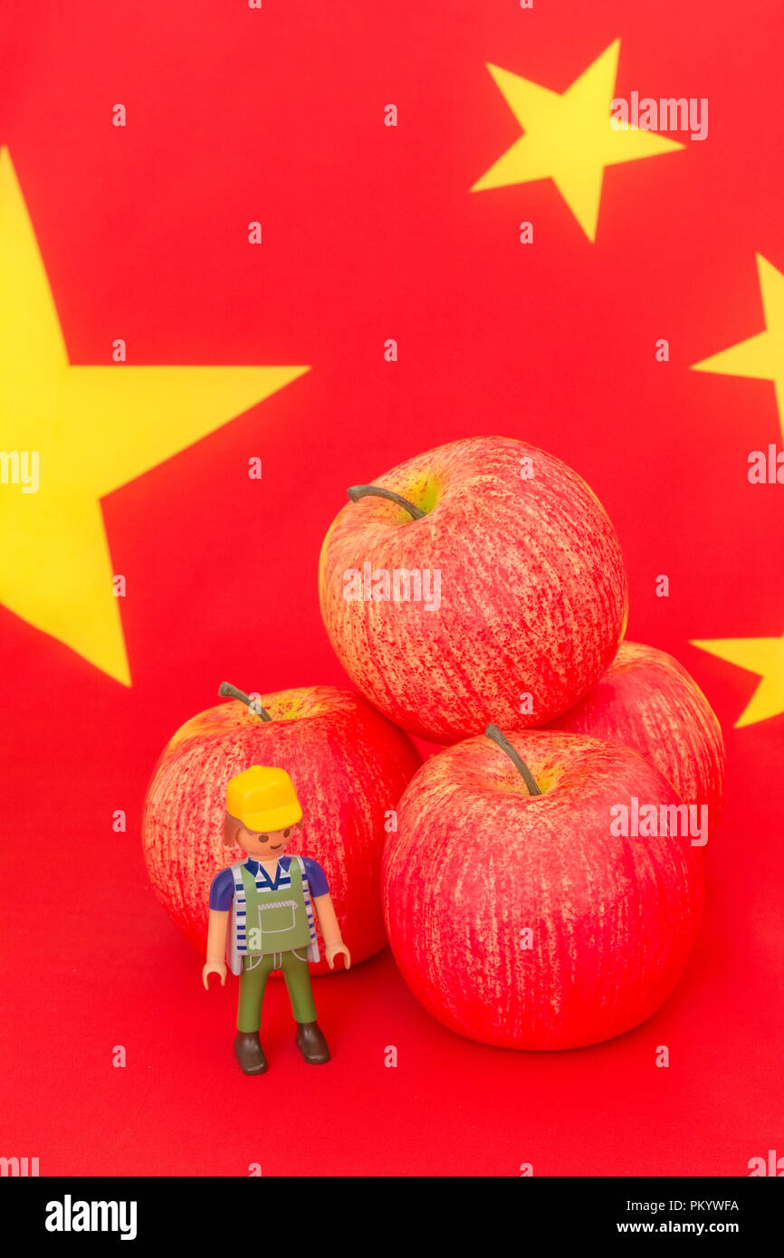 Noi di Apple in rosso le esportazioni con bandiera cinese e piccolo giocattolo agricoltore - metafora noi apple Industria, commercio cinese tariffe doganali sulle importazioni di noi le mele. Foto Stock