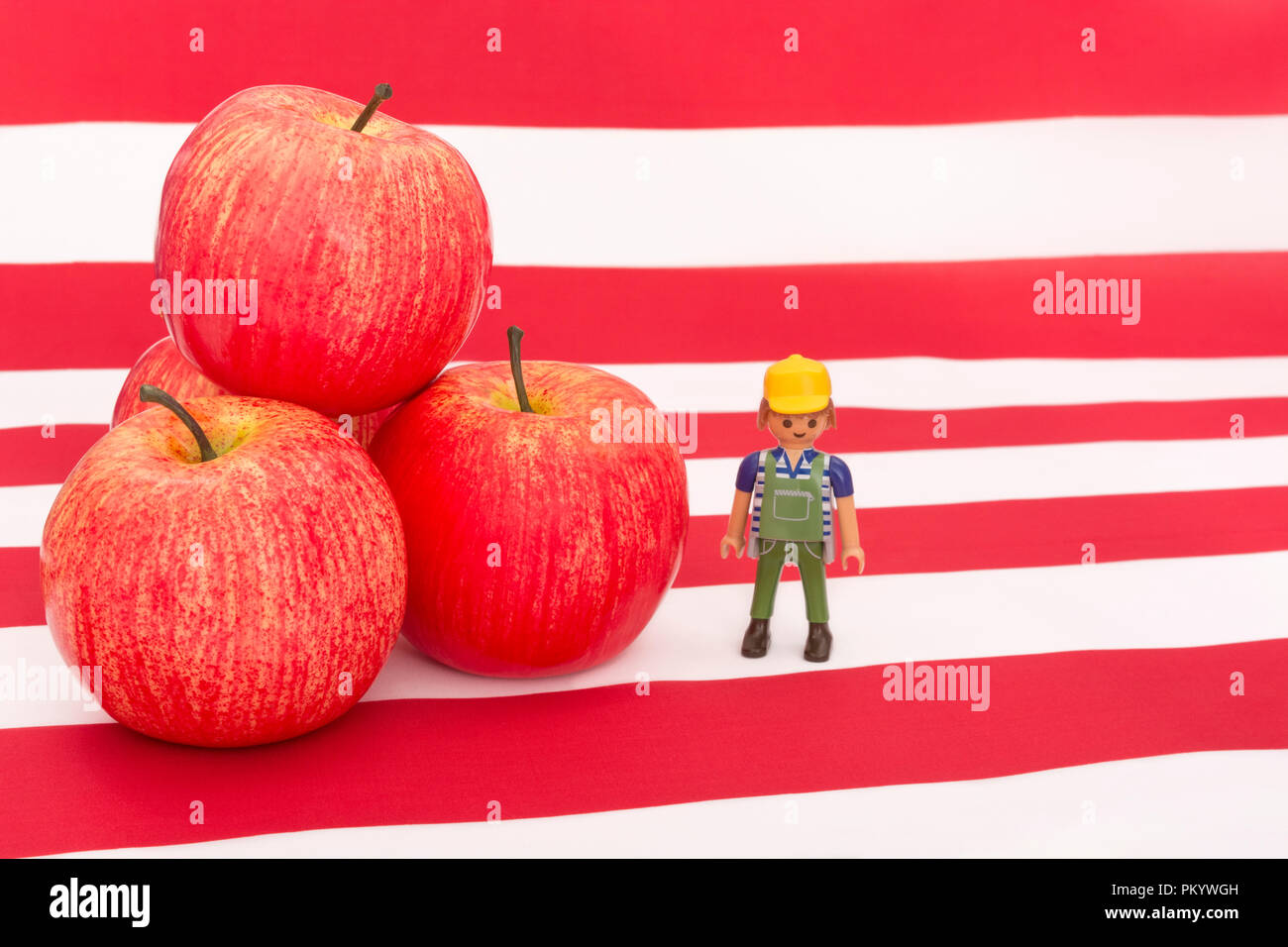 Red Apples & US American flag / Stelle & Stripes. Esportazioni alimentari statunitensi, industria delle mele americana, dazi commerciali cinesi sulle importazioni di mele statunitensi. Piccolo coltivatore di giocattoli Foto Stock