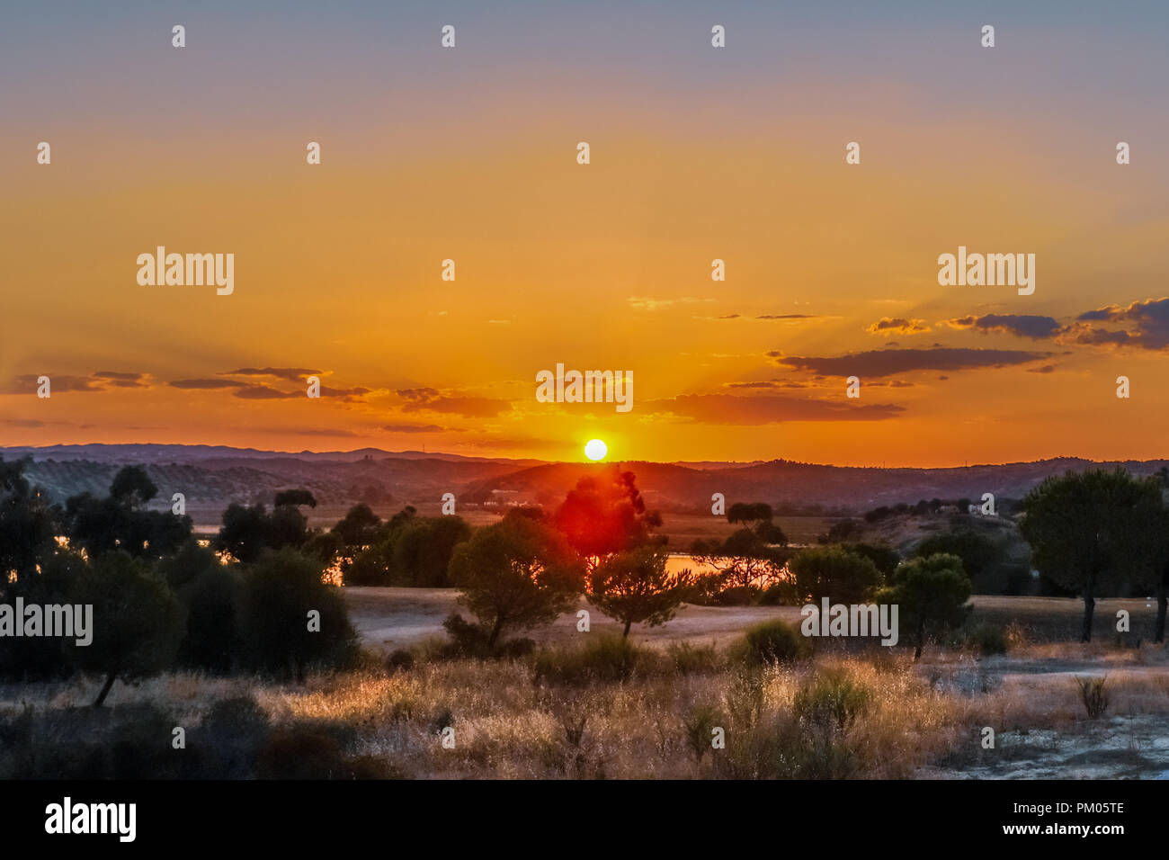 Tramonto Dorato con raggi nella foschia e nuvole in Ayamonte Andalusia cercando di fronte al Portogallo oltre il Fiume Guadiana visto dalla Costa Esuri Foto Stock