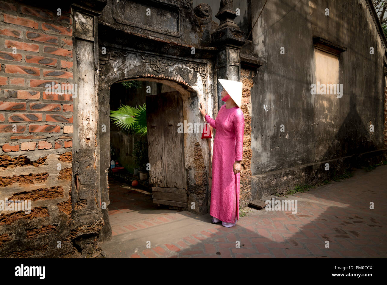 Una donna affascinante in un tradizionale ao dai in borgo antico di Duong Lam. Hanoi, capitale del Vietnam Foto Stock