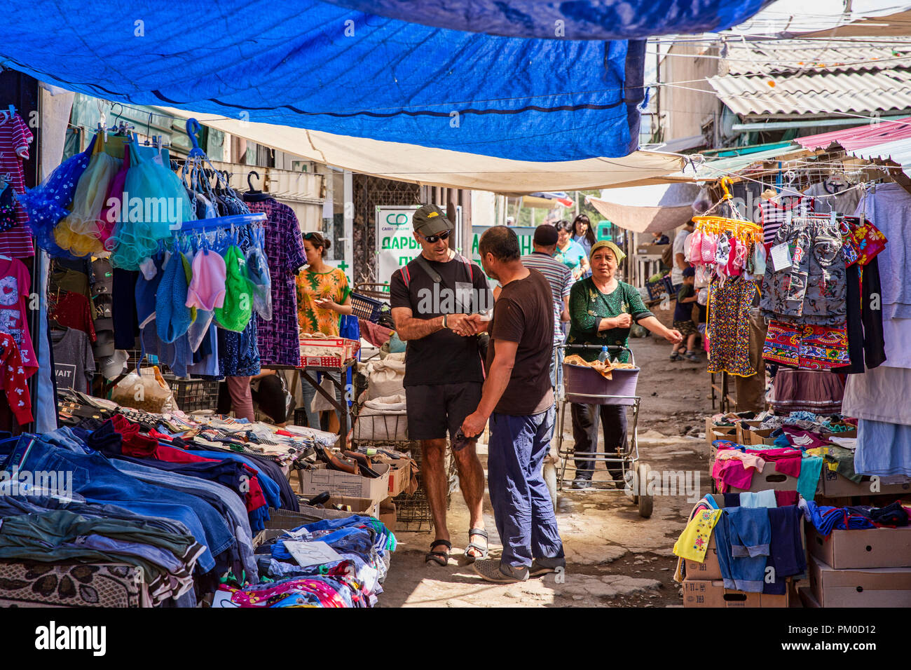 Locale uomo del Kirghizistan saluto e stringe la mano ad un turista nel grande Bazaar a Karakol, Kirghizistan. Foto Stock