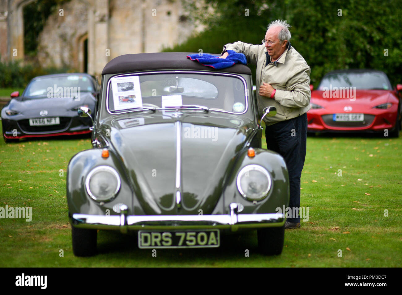 Un uomo delle salviette pioggia dal suo scarabeo di Volkswagen dopo una doccia a un auto classica raduno al Castello di Sudeley nel Cotswolds. Foto Stock
