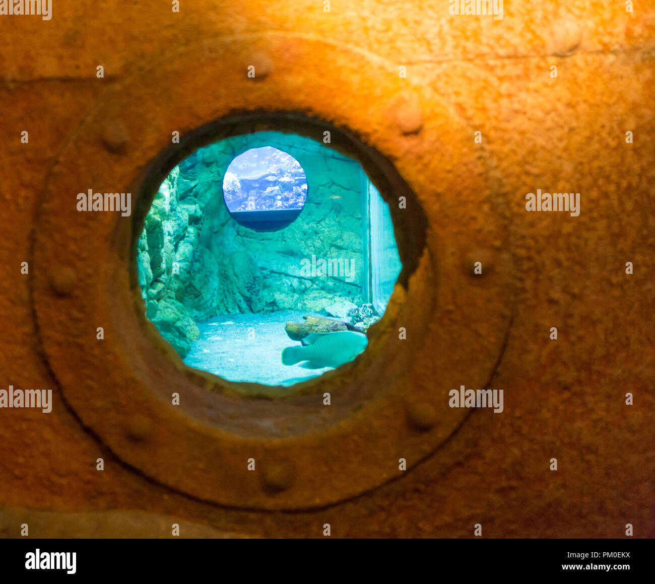 Arrugginita striate oblò rotondo nel lato di un vecchio dipinto di bianco di nave con superficie blu nella parte inferiore Foto Stock