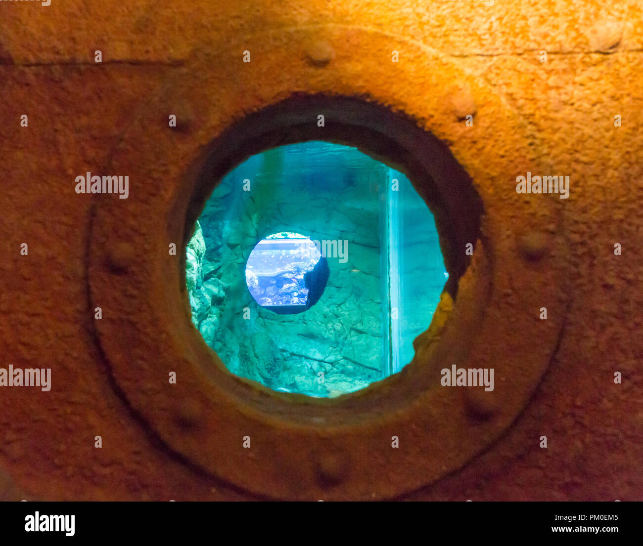 Arrugginita striate oblò rotondo nel lato di un vecchio dipinto di bianco di nave con superficie blu nella parte inferiore Foto Stock