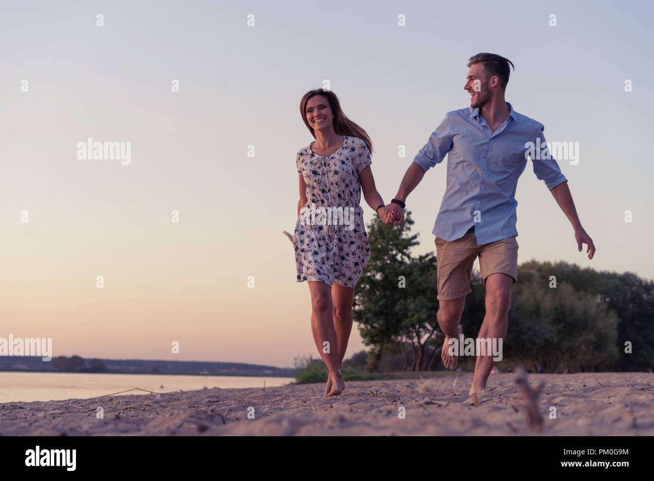 Paio di camminare sulla spiaggia al tramonto Foto Stock