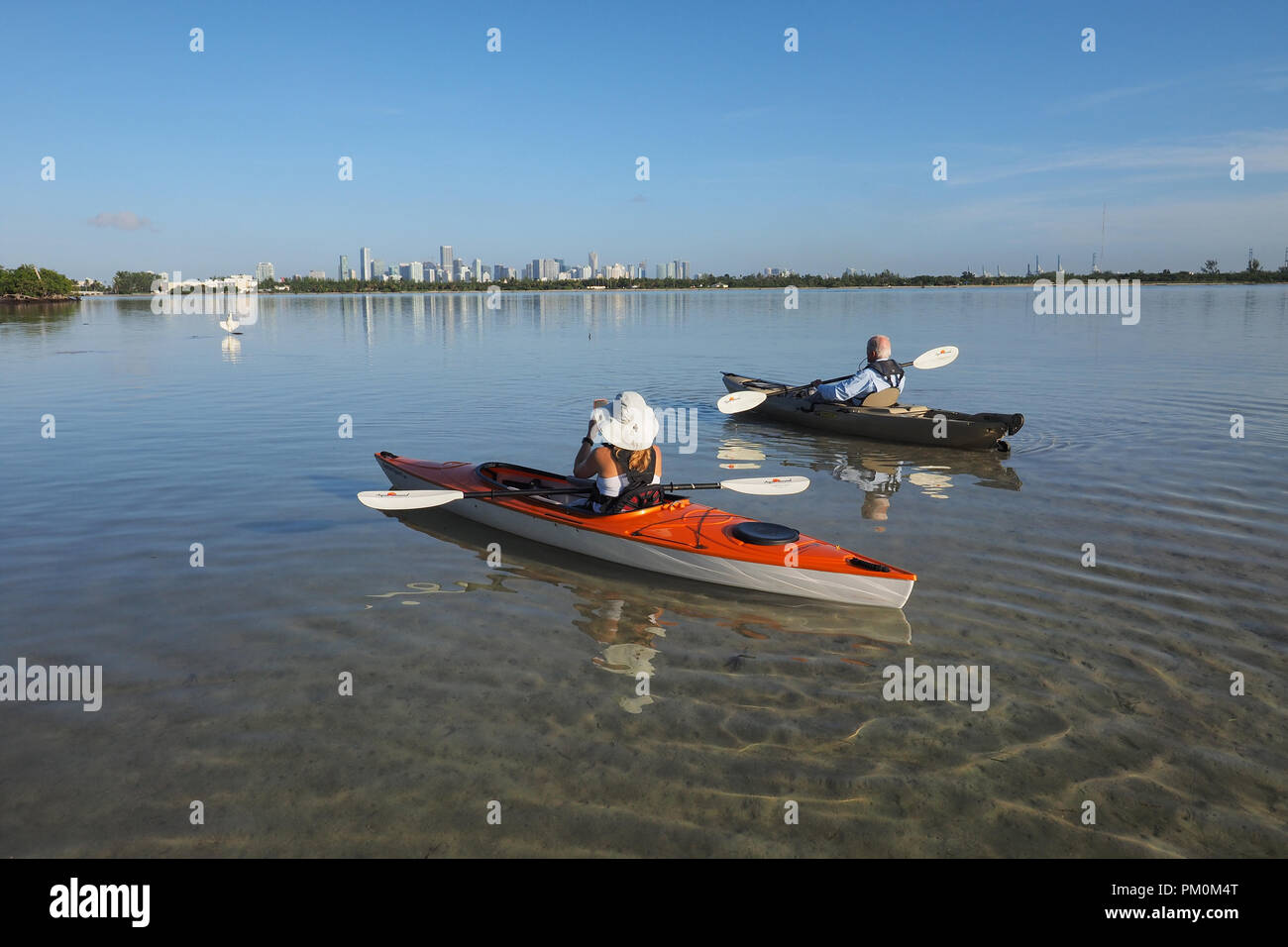 Donna e active senior kayak su molto calma acqua in orso cut off Key Biscayne, Florida con la città di skyline di Miami in background. Foto Stock