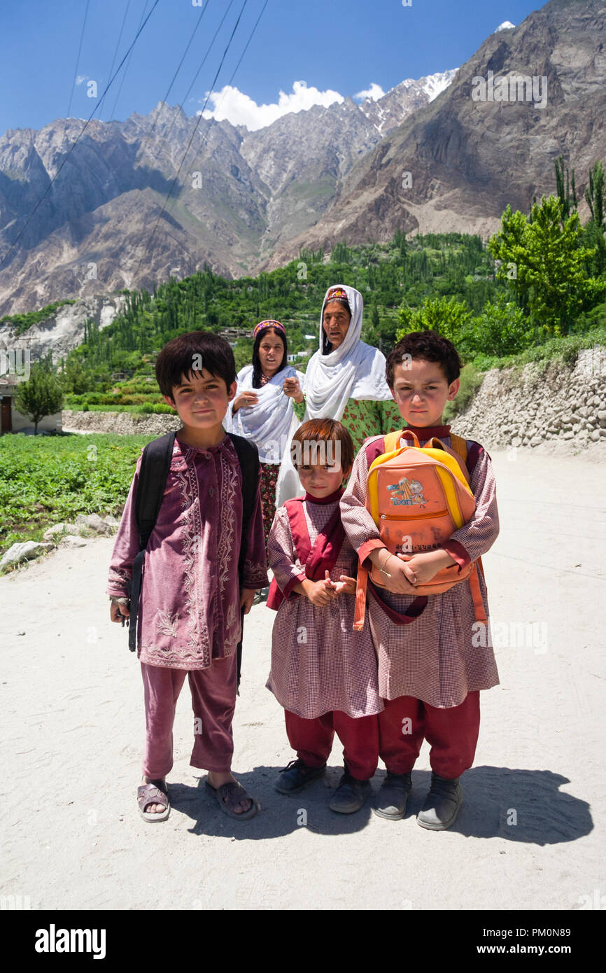 Karimabad, Hunza Valley, Gilgit-Baltistan, Pakistan : due donne e tre bambini di scuola sul loro modo home posare per un ritratto sulla strada da Altit Foto Stock