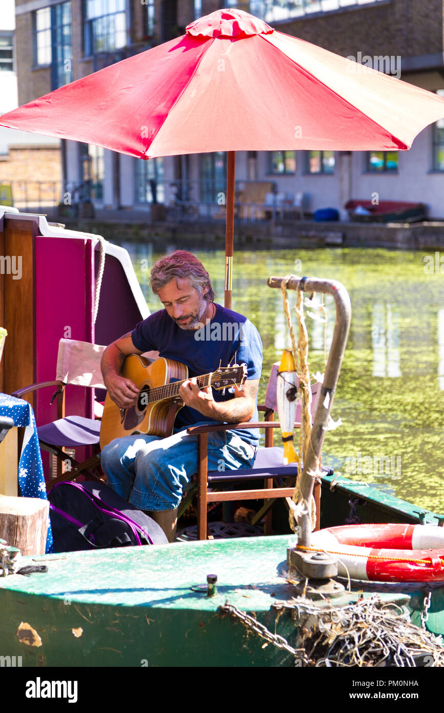 Uomo a suonare la chitarra su un ormeggio narrowboat presso Angel Canal Festival, London, Regno Unito Foto Stock