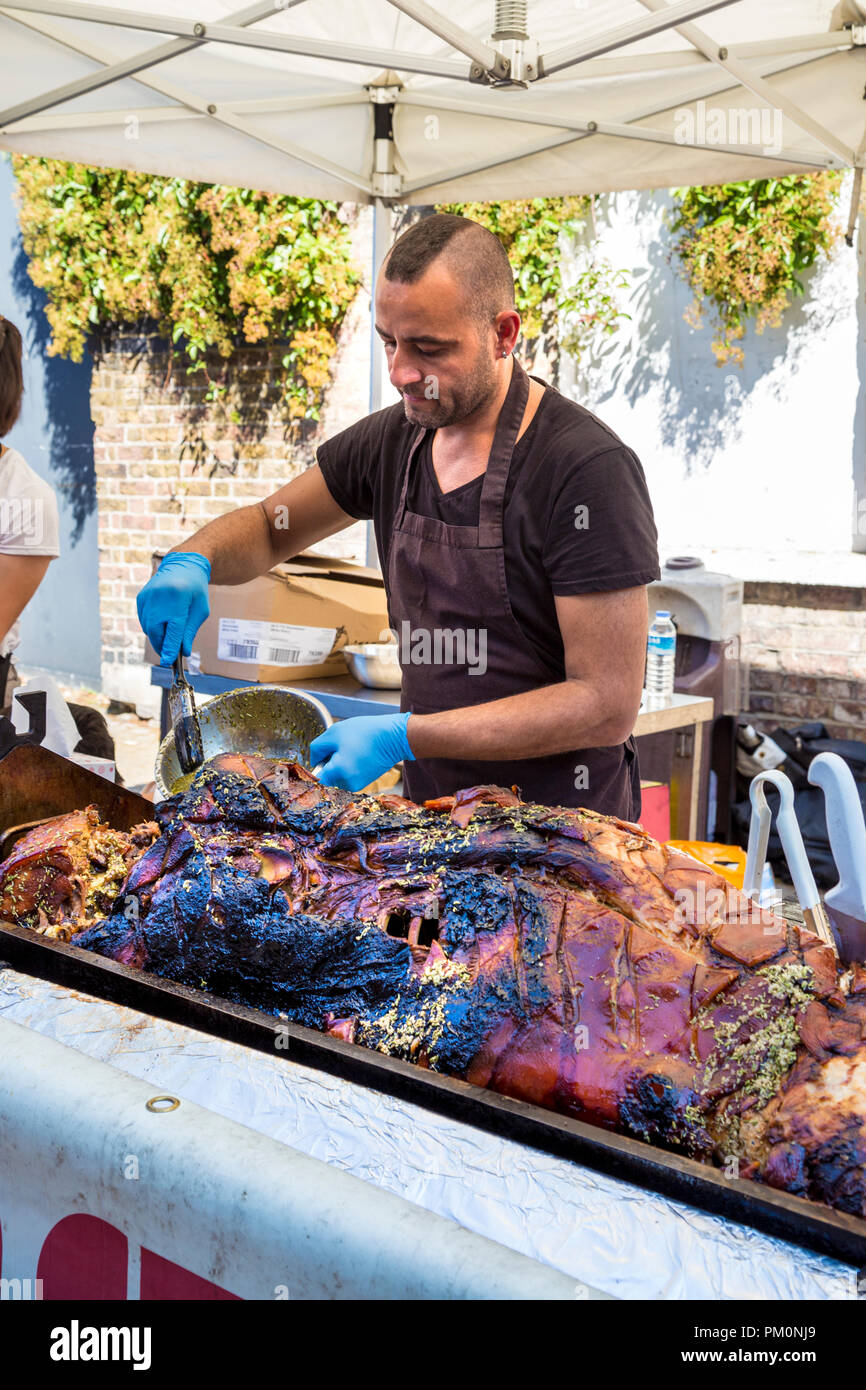 L'uomo inumidendo un arrosto di maiale a Angel Canal Festival 2018, London, Regno Unito Foto Stock
