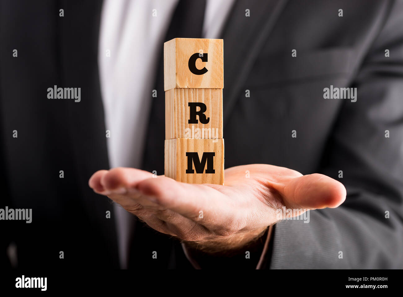 Gestione delle relazioni con i clienti - Imprenditore mostra piccoli blocchi di legno a portata di mano con il CRM acronimo testi. Foto Stock