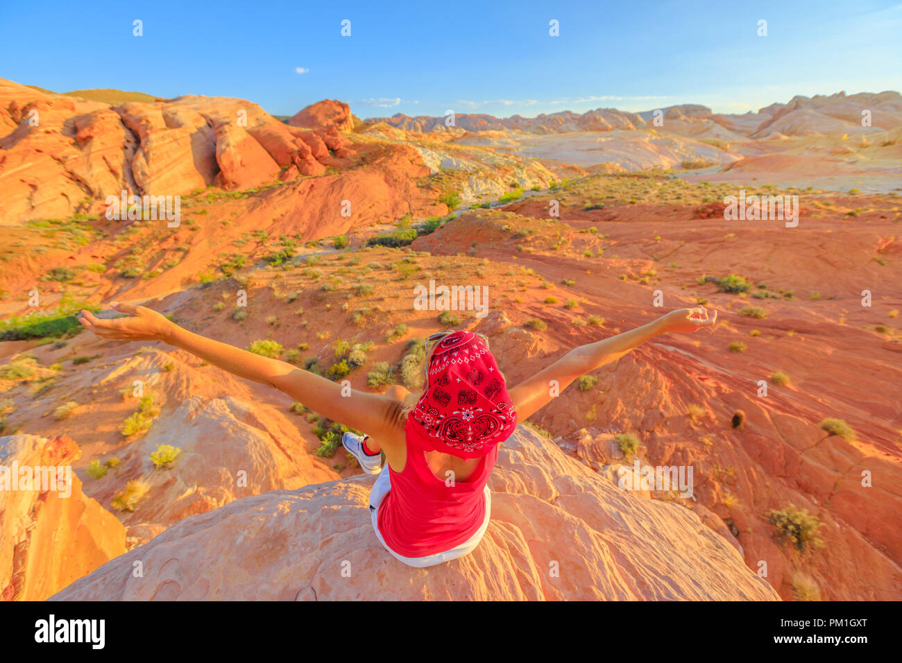 Libertà escursionismo donna alla Valle del Fuoco del parco statale sulla sommità del fuoco onda al tramonto. Felice escursionista gode di vedute panoramiche di nastri di red rock slice attraverso il paesaggio del deserto. Nevada, Stati Uniti. Foto Stock