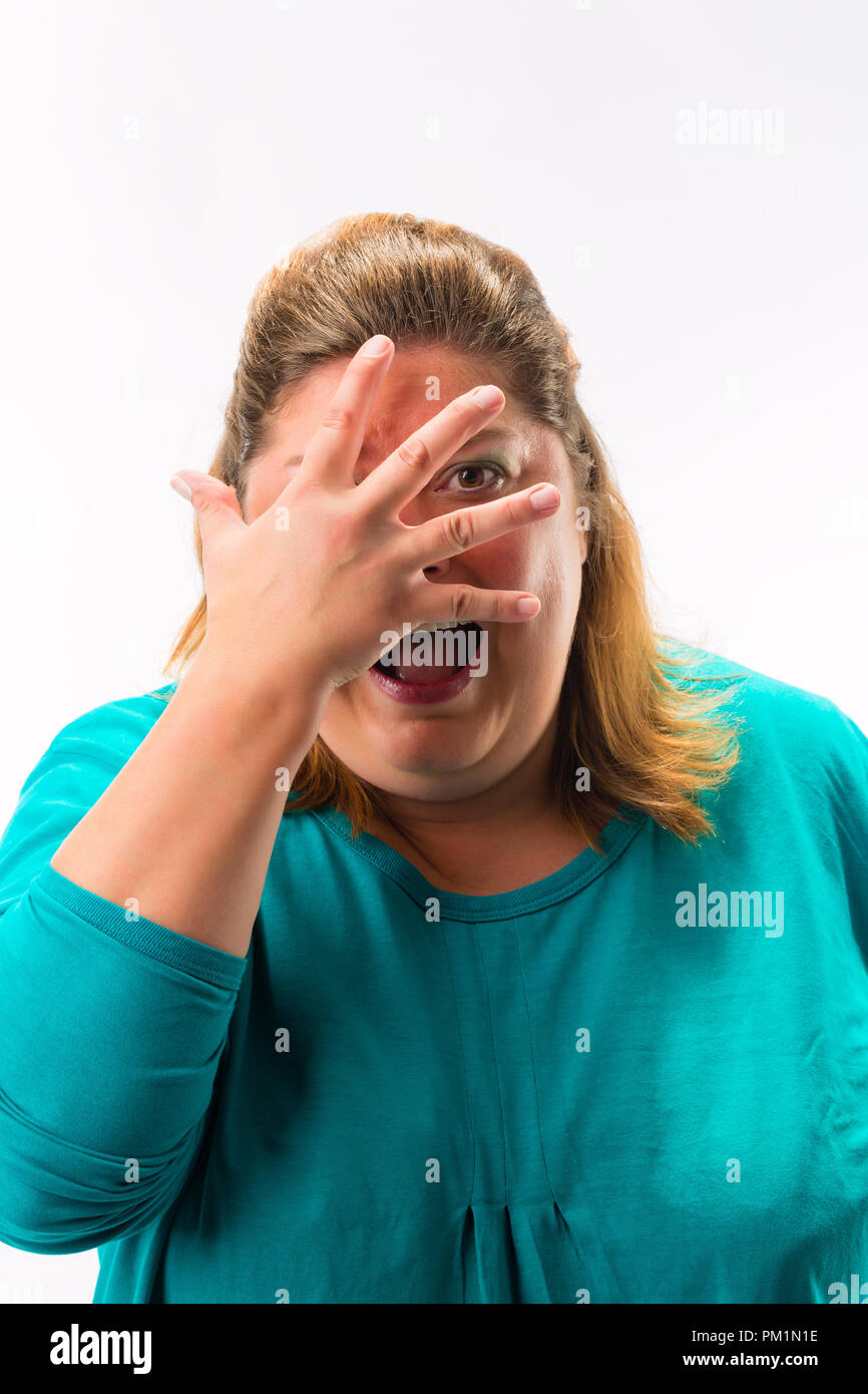Spaventata donna spiata da dita sopra la faccia Foto Stock