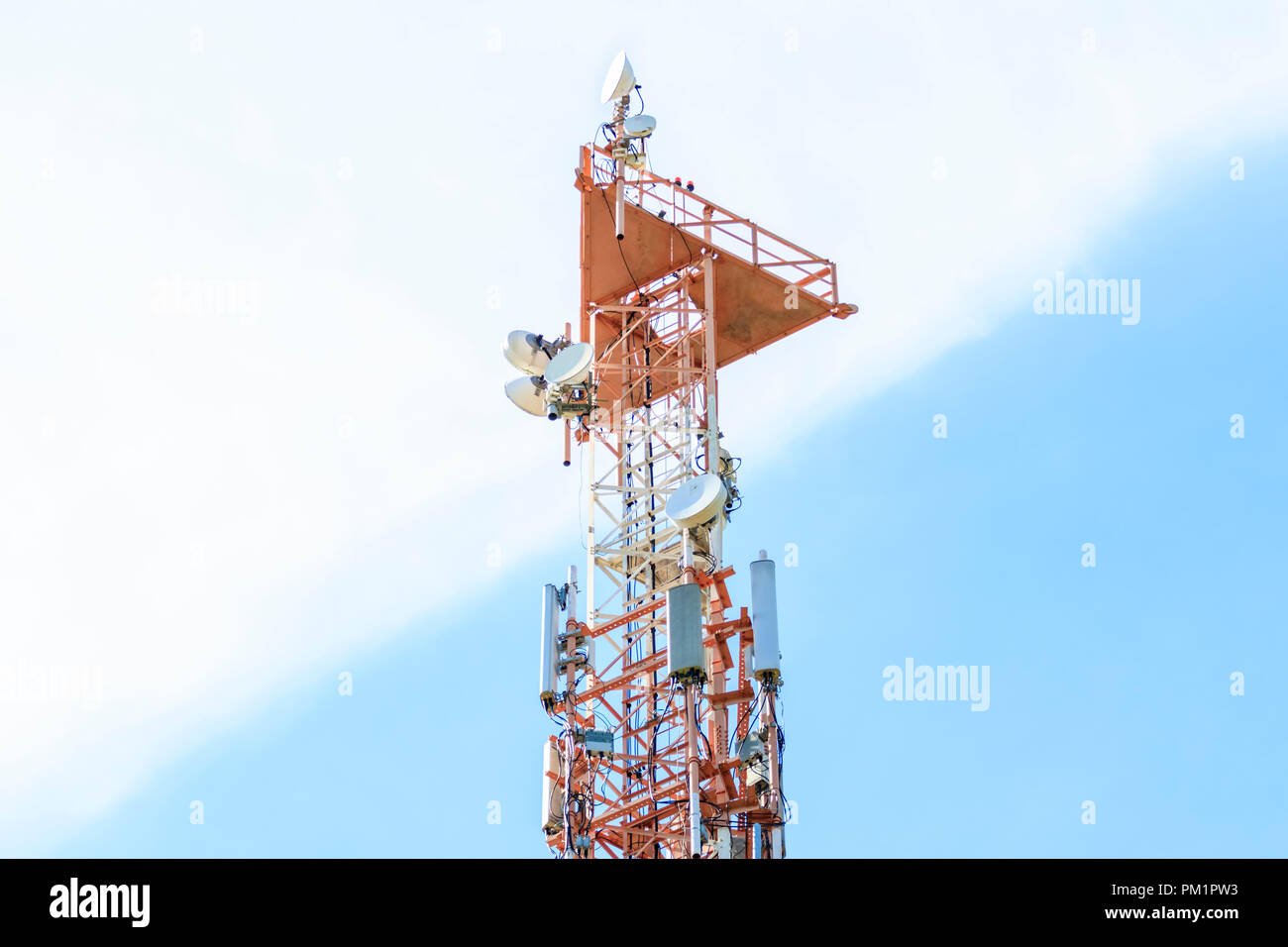 Telecomunicazioni cellulari e torre radio, blu e sfondo con cielo nuvoloso Foto Stock