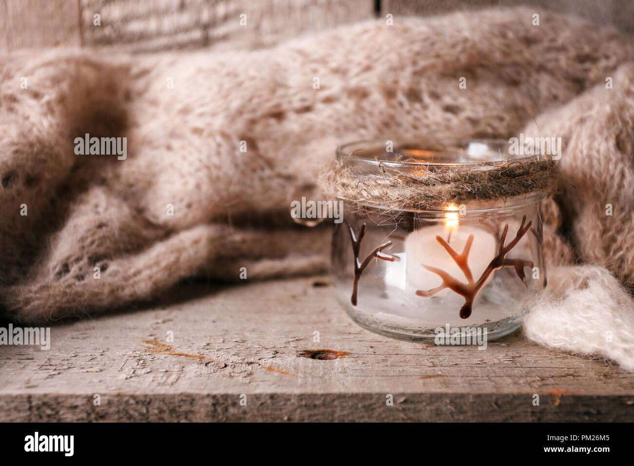 Accogliente lana autunno inverno cadono accessorio. Caldo e pleid candela su una tavola di legno. Autentica atmosfera tranquilla. Kinfolk Hygge Slow Living Style. Foto Stock