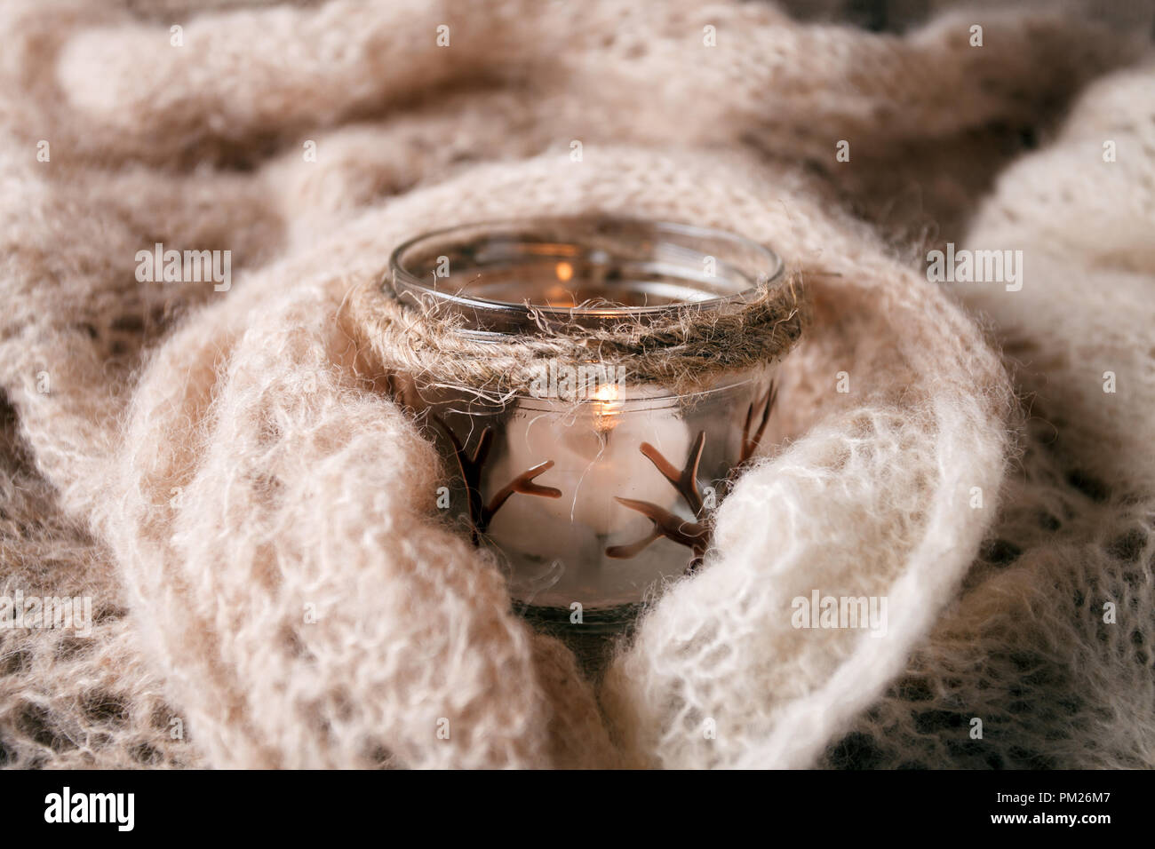 Candela accesa bianco Felpa lavorata a maglia sul listone legno tabella dalla finestra. Accogliente autunno inverno sera. Luce naturale autentica atmosfera tranquilla. Kinfolk Hygge Foto Stock
