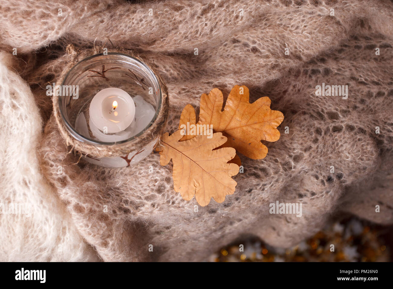 La luce di una candela,sciarpa rosa su uno sfondo di legno. Inverno cosiness umore, vista dall'alto, accogliente autunno inverno sera Foto Stock