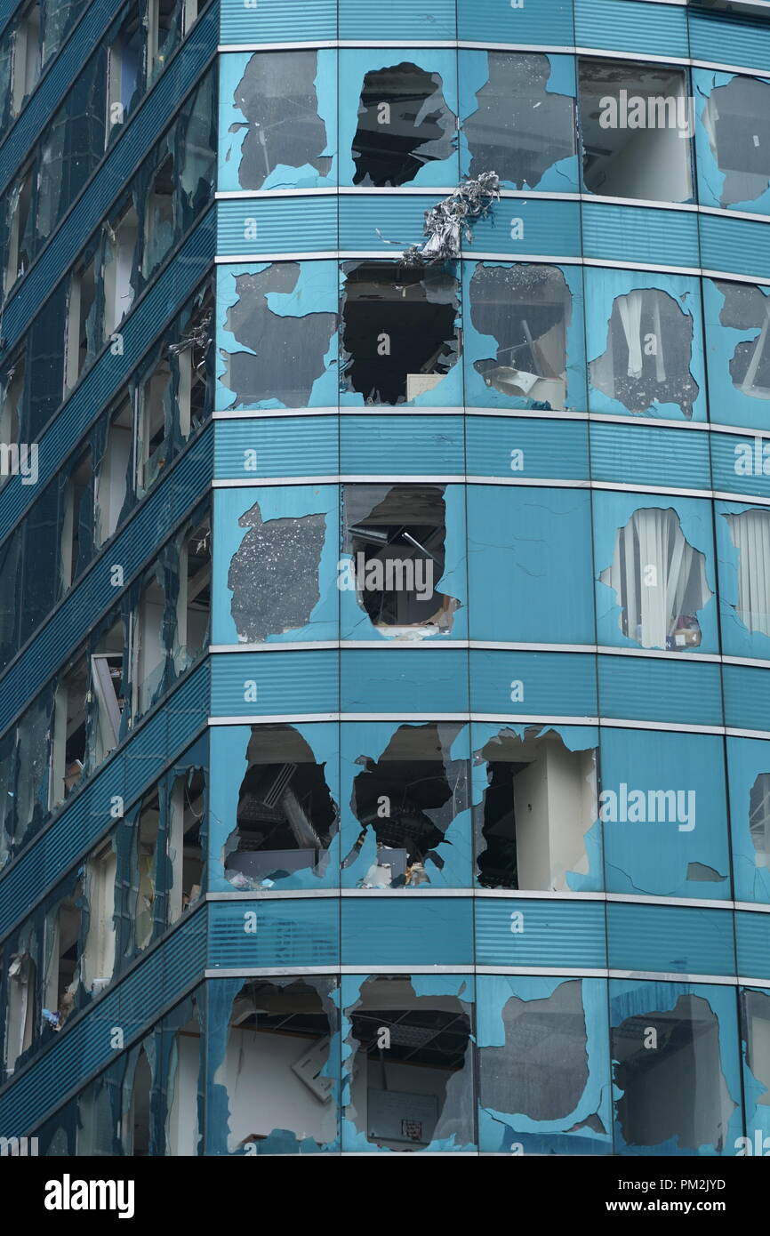 Primo piano di finestre frantumate su un alto edificio di Hong Kong durante il Typhoon Mangkhut nel 2018. La potente tempesta ha causato danni significativi in tutta la città, con finestre di vetro rotte che rivelano la forza distruttiva del ciclone tropicale. Questa immagine evidenzia la vulnerabilità delle infrastrutture urbane agli eventi meteorologici estremi e il grave impatto del tifone Mangkhut sugli edifici residenziali e commerciali. Foto Stock