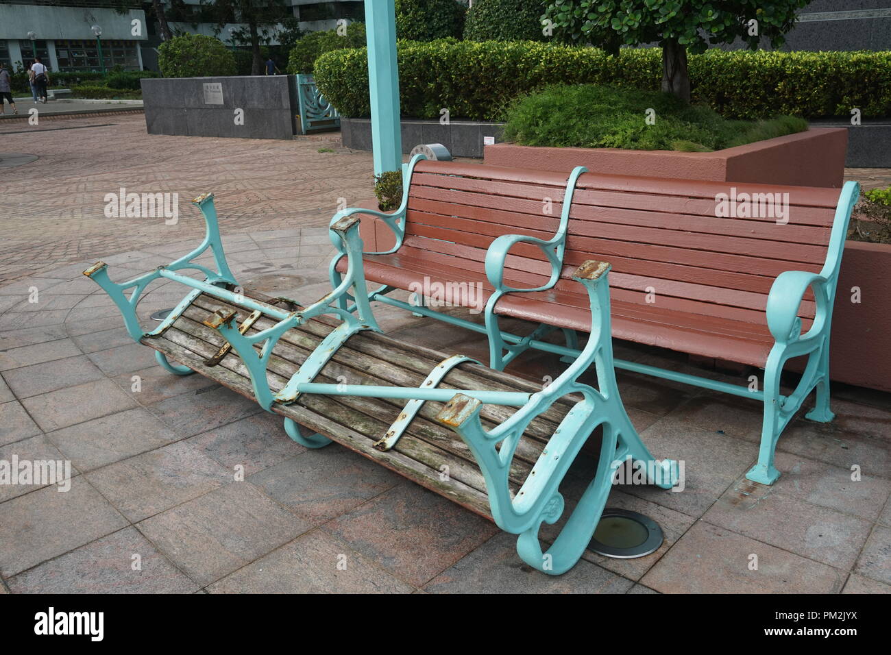 Panchine del parco di Hong Kong danneggiate dal tifone Mangkhut nel 2018. Una panchina è rovesciata, illustrando la potente distruzione causata dalla tempesta tropicale. L'immagine mette in evidenza il grave impatto delle condizioni meteorologiche estreme sugli spazi pubblici urbani, con danni visibili alle infrastrutture esterne in un ambiente urbano di parco. Foto Stock