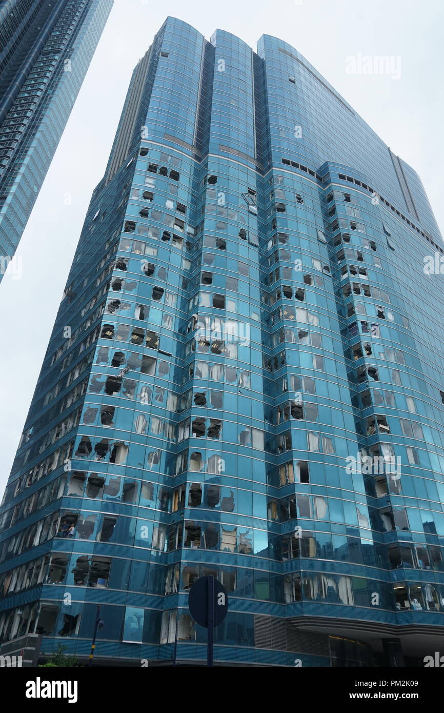 Finestre di vetro di un alto edificio commerciale frantumato dal tifone Mangkhut di Hong Kong durante la tempesta del 2018. Il potente ciclone tropicale causò distruzione diffusa in tutta la città, compresa la rottura delle facciate di vetro sui moderni grattacieli. Questa immagine illustra l'impatto devastante e la forza distruttiva degli eventi meteorologici estremi sulle infrastrutture urbane in una delle città più densamente popolate dell'Asia. Foto Stock