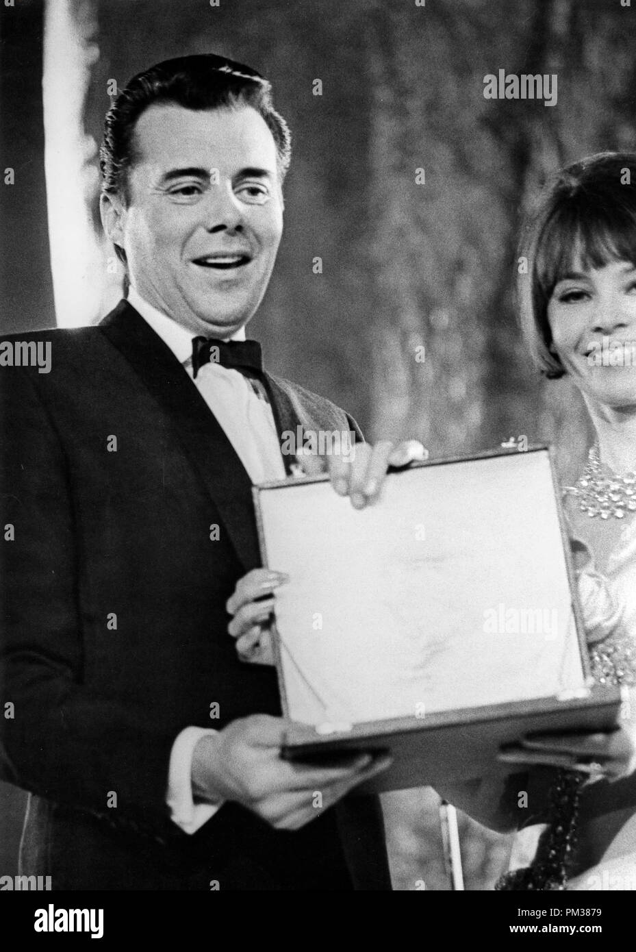 Dirk Bogarde raccoglie i suoi British Film Academy Award per il miglior attore britannico da Leslie Caron, marzo 1966. Riferimento al file # 1166 001THA © CCR /Hollywood Archivio - Tutti i diritti riservati Foto Stock