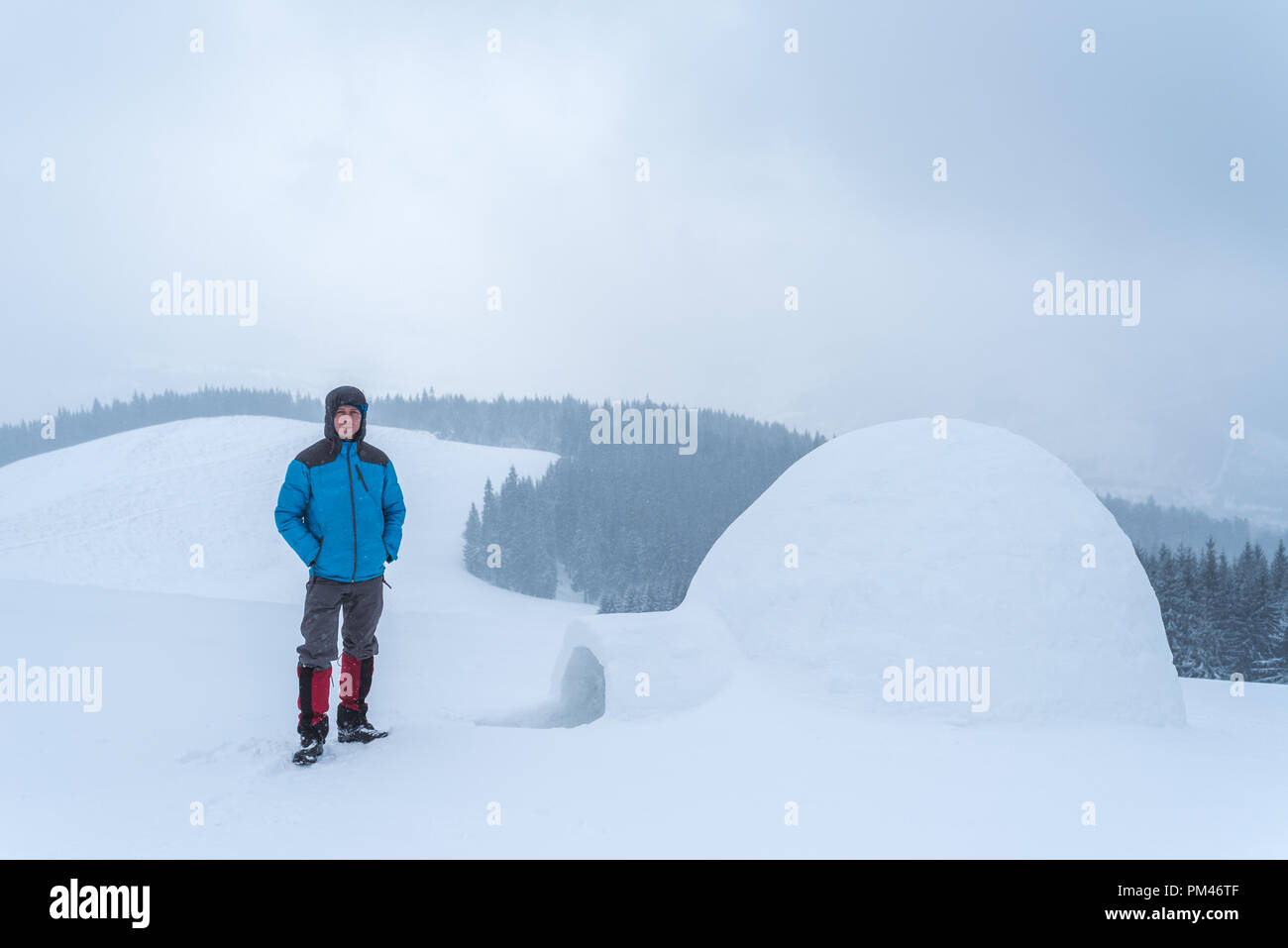 Guy ha costruito un igloo in montagna. Avventure invernali in escursione. Paesaggio con un vago giorno nuvoloso Foto Stock