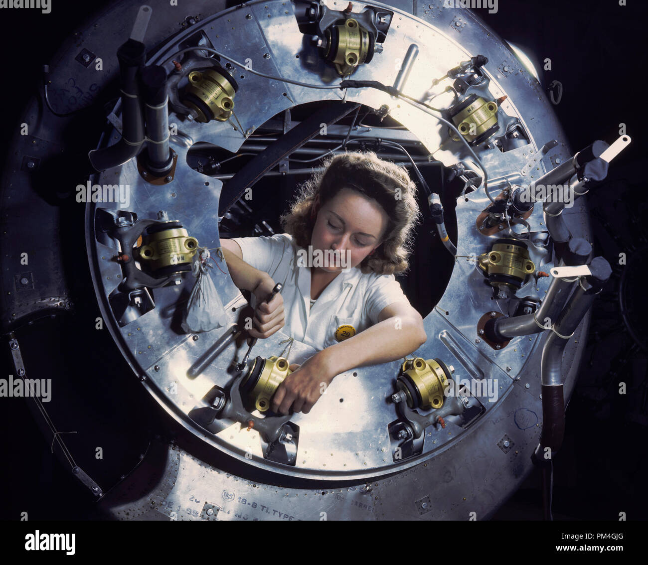 Un lavoratore di sesso femminile si concentra sulla parte del cofano per uno dei motori di un B-25 bombardiere essendo montati nel motore dipartimento del Nord America (Aviazione, Inc.) Inglewood, CA, impianto, 1942. Riferimento al file # 1003 0,35 THA Foto Stock
