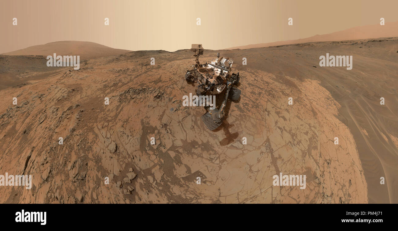 Questo autoritratto della NASA Curiosità Mars rover mostra il veicolo presso il 'Mojave' sito, dove praticare il suo raccolto la missione secondo il gusto del monte Sharp. La scena unisce decine di immagini prese durante il mese di gennaio 2015 dal Marte lente mano Imager (MACLI) fotocamera alla fine del rover del braccio robotico. Il pallido 'Pahrump Hills' affioramento circonda il rover, e la porzione superiore del monte Sharp è visibile all'orizzonte. La massa scura in alto a destra e in basso a sinistra contiene increspature di vento-soffiato di sabbia e polvere. Riferimento al file # 1003 575THA Foto Stock