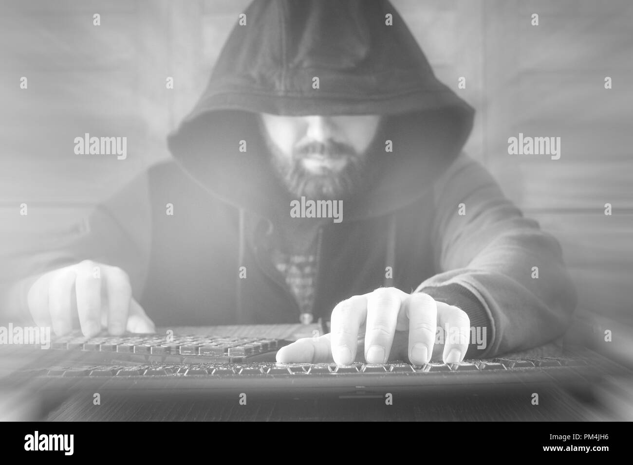 Il pirata informatico nel cofano si siede e lavora dietro il computer Foto Stock
