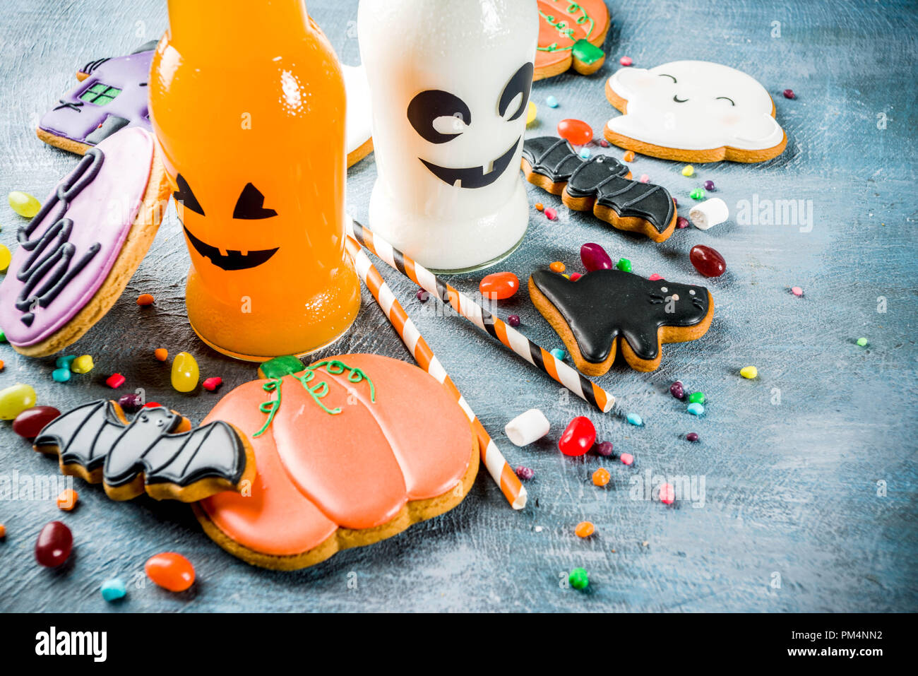 Considera i bambini per la festa di Halloween, funny fatti in casa i cookie di vetrate, varie caramelle latte e succo di frutta in bottiglia monster, blu sfondo concreto spazio copia vi superiore Foto Stock