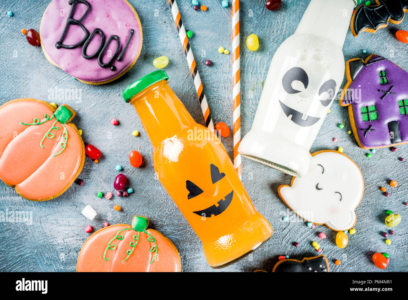 Considera i bambini per la festa di Halloween, funny fatti in casa i cookie di vetrate, varie caramelle latte e succo di frutta in bottiglia monster, blu sfondo concreto spazio copia vi superiore Foto Stock