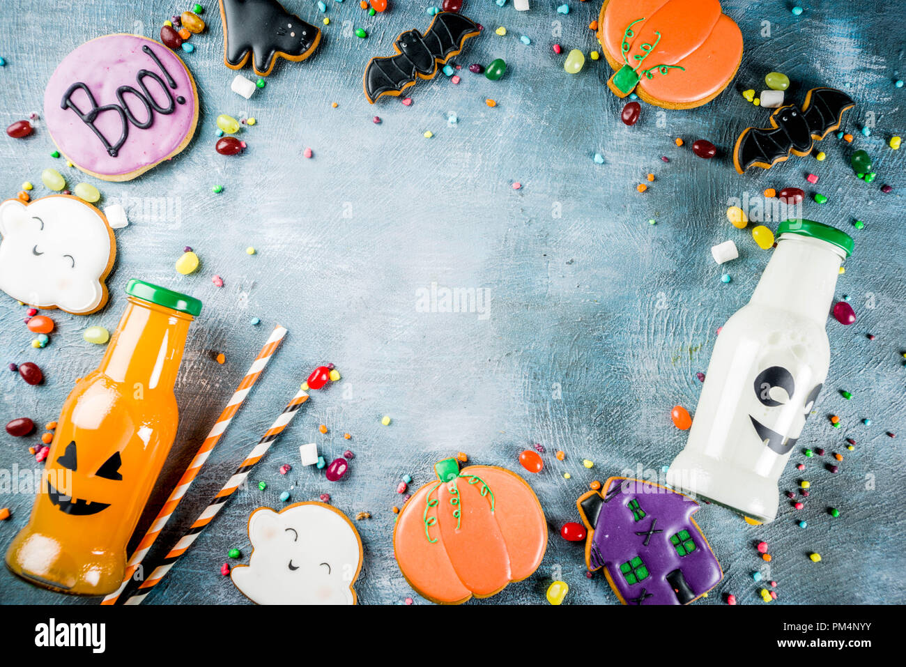 Considera i bambini per la festa di Halloween, funny fatti in casa i cookie di vetrate, varie caramelle latte e succo di frutta in bottiglia monster, blu sfondo concreto spazio copia vi superiore Foto Stock