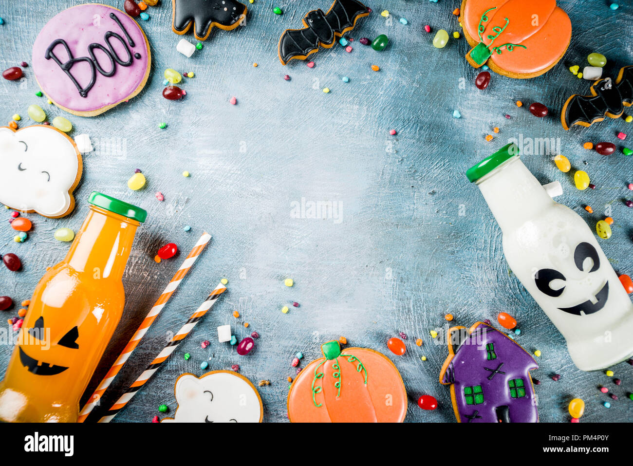Considera i bambini per la festa di Halloween, funny fatti in casa i cookie di vetrate, varie caramelle latte e succo di frutta in bottiglia monster, blu sfondo concreto spazio copia vi superiore Foto Stock