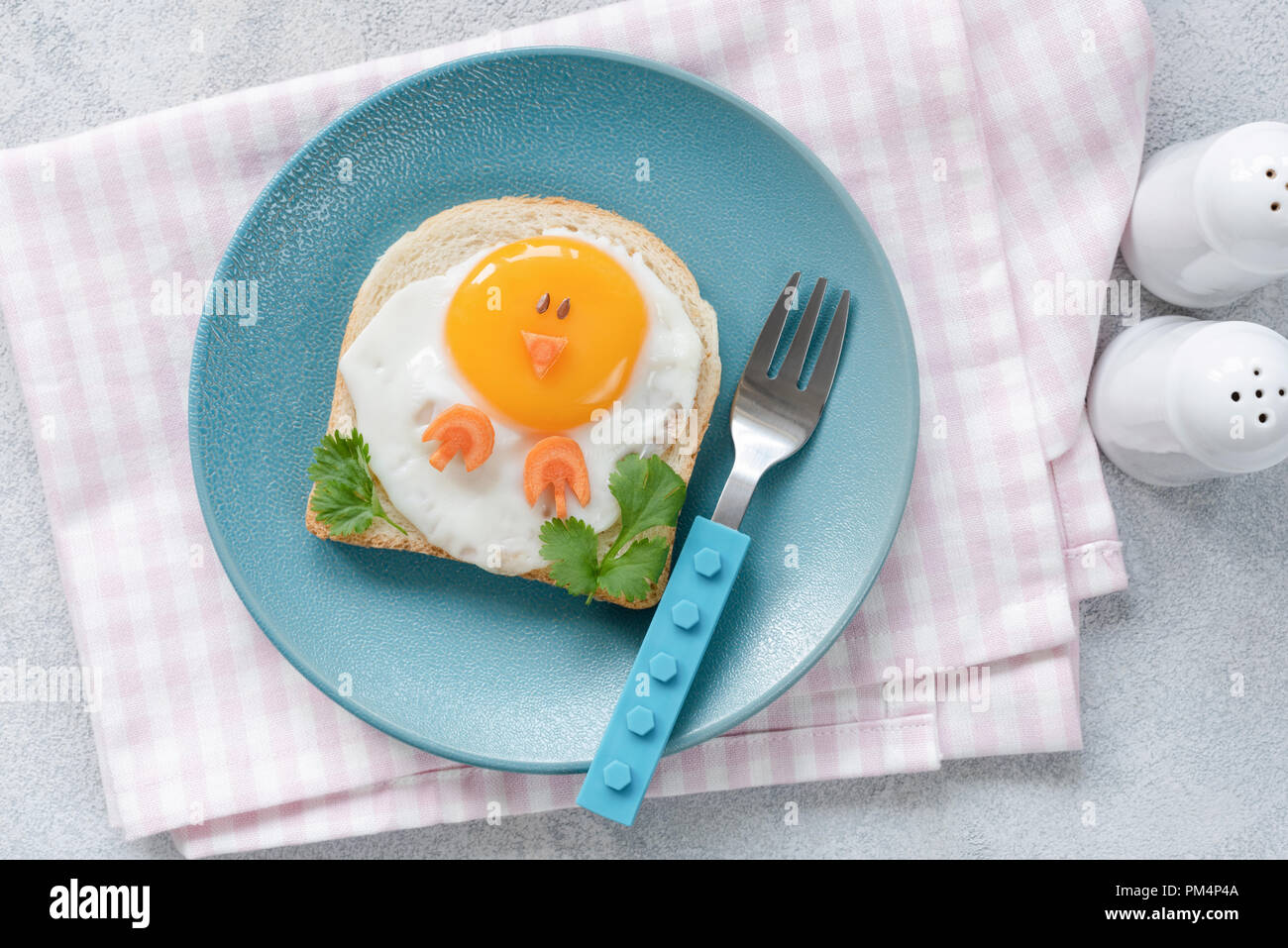 La prima colazione per i bambini. Uovo toast con divertenti carino arte cibo su una piastra di blu. Vista superiore Foto Stock