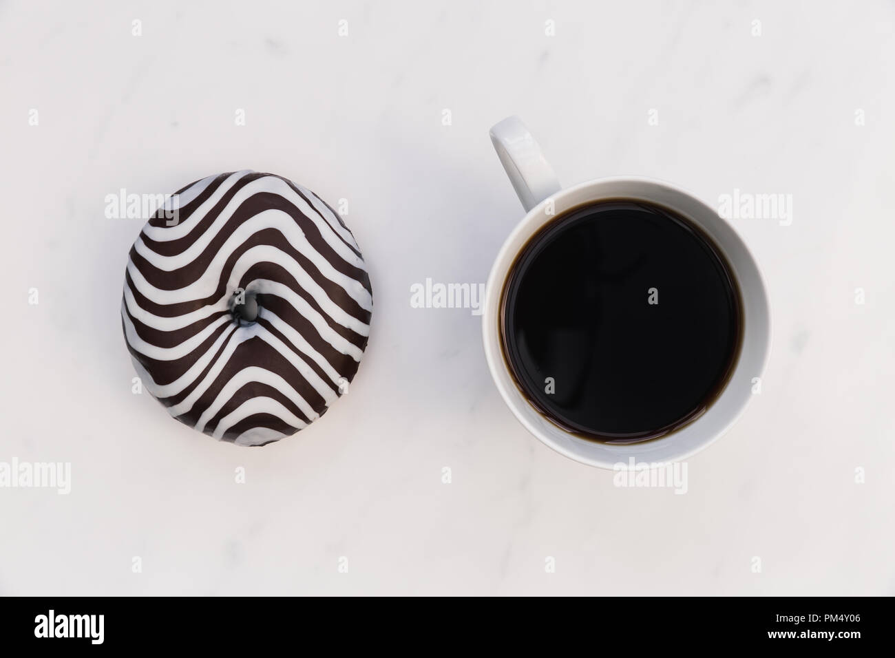 Ciambella a strisce e la tazza di caffè su sfondo bianco Foto Stock