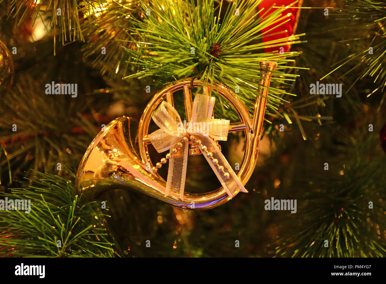 Splendido oro lucido corno francese a forma di nastro con archetto ornamento di Natale appeso sul scintillante albero di Natale Foto Stock
