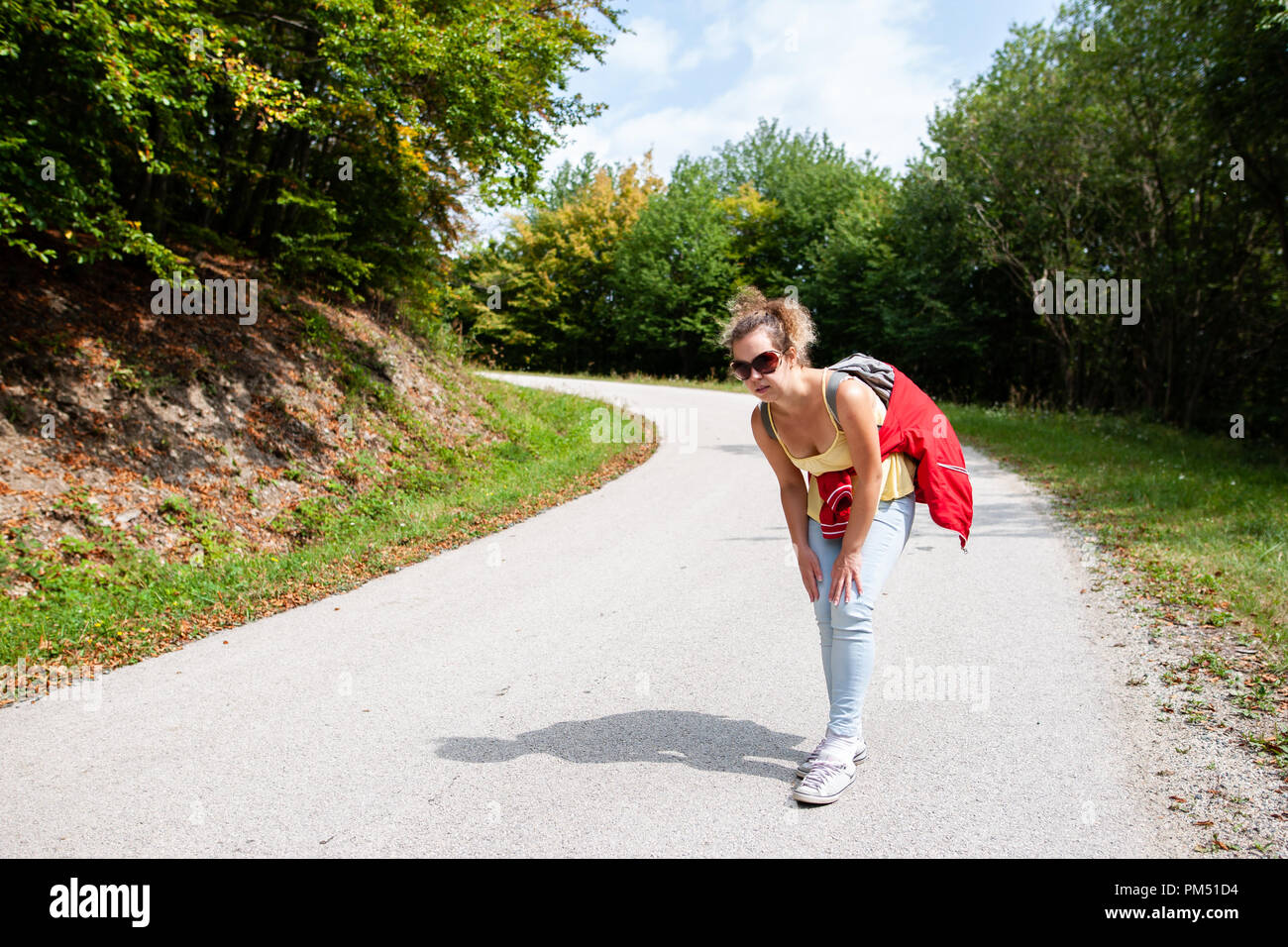 Donna di viaggiatori stanchi e fanno male le gambe da ha perso il suo titolo nella foresta in estate Foto Stock