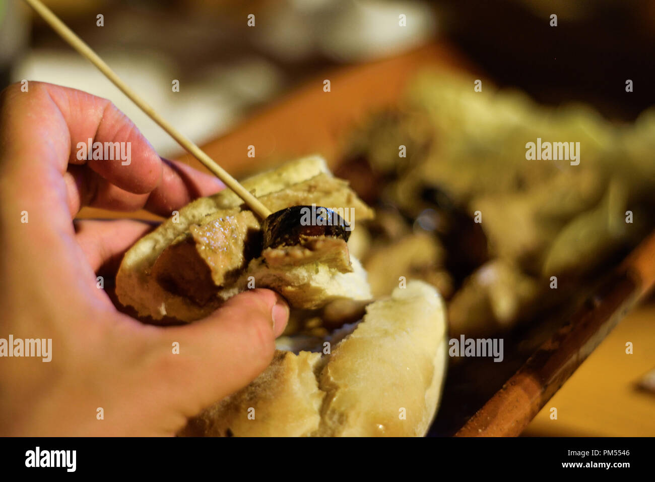 Tapas e grigliate tradizionali portoghesi. Cibo di strada consumato in Portogallo, uomo che tiene un panino con carne alla griglia. Sandwich Street food. Foto Stock