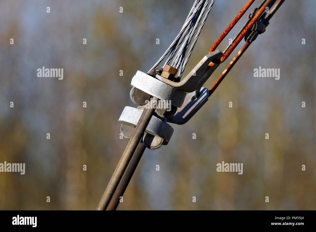 Vecchia connessione. Chiudere la foto di rusty tenditore di linee di alimentazione. Una filiera asta collegata a steele cavi. Isolato dal marrone scuro dello sfondo Foto Stock