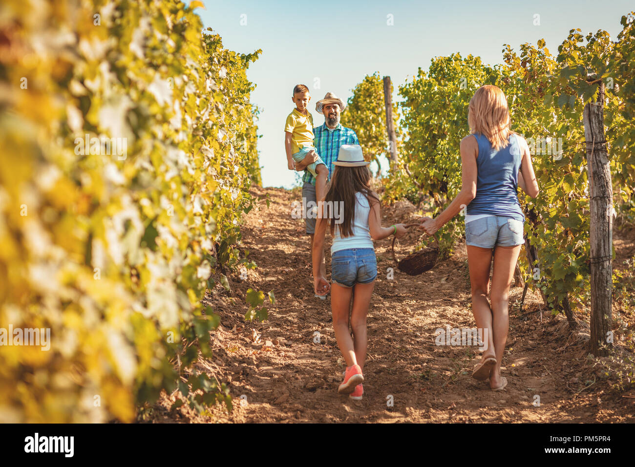 Giovane e bella famiglia sorridente di quattro uve di taglio in corrispondenza di una vigna. Foto Stock