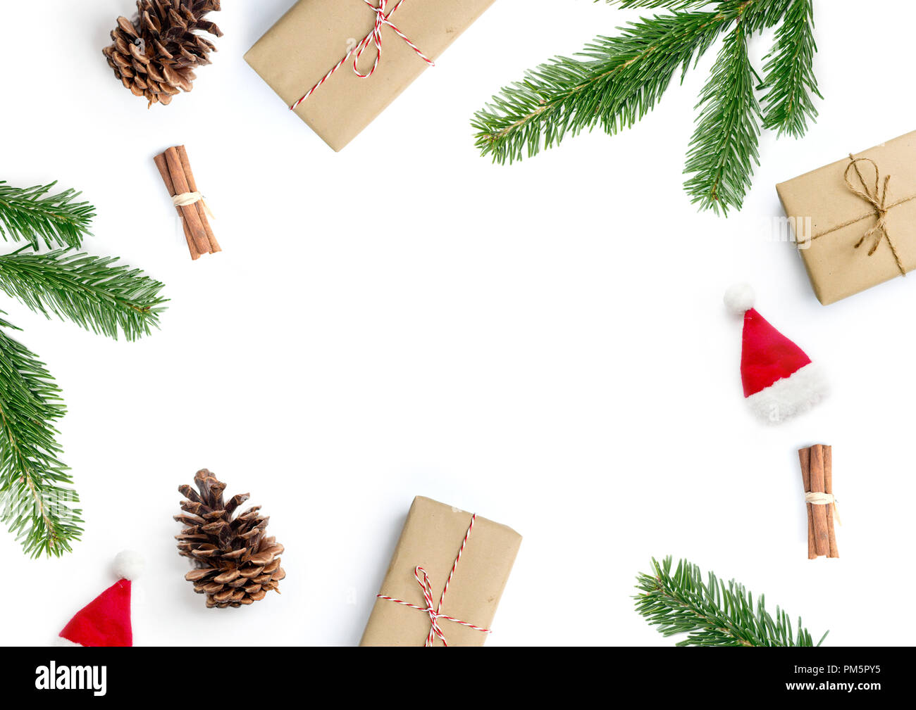 Buon Natale composizione layout, vista dall'alto con il natale presenta, bastoncini di cannella, Abete rami e pigne su uno sfondo bianco. Foto Stock