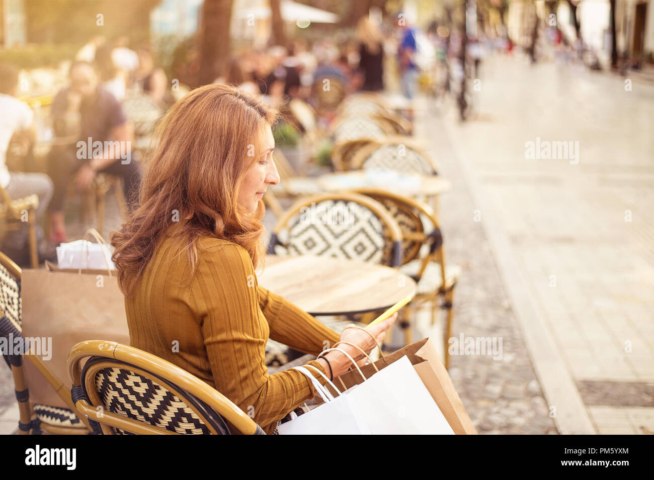 Shopper donna shopping a mano con uno smart phone e il trasporto del bagaglio Foto Stock