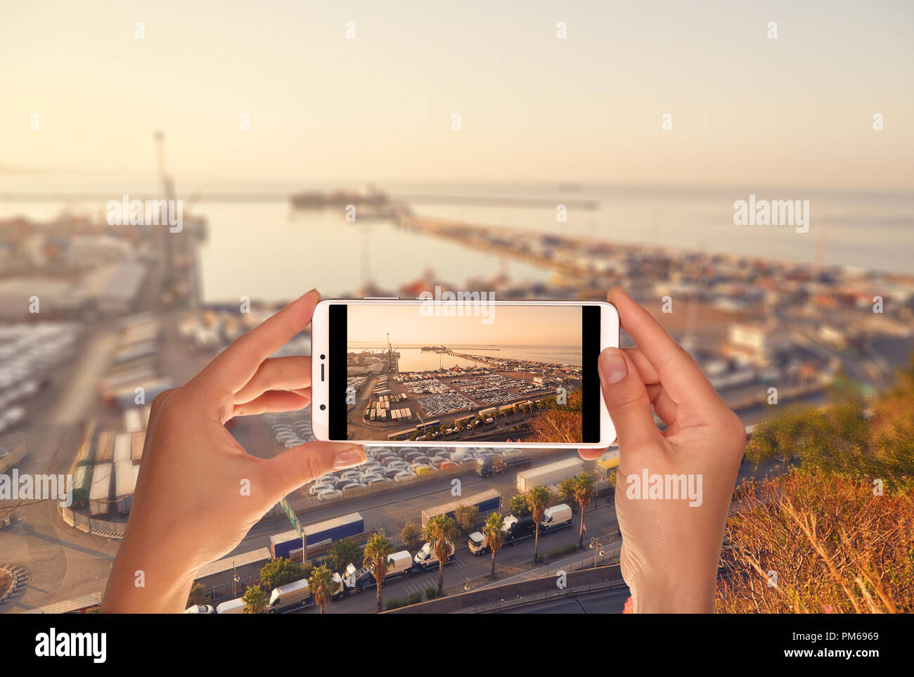 Un turista è scattare una foto della porta di carico terminale con un grande numero di contenitori su un telefono cellulare Foto Stock