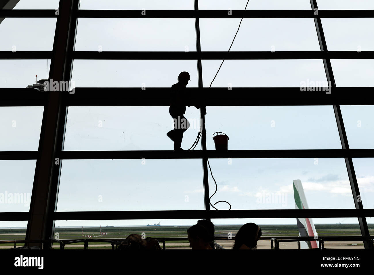 Silhouette colpo di pulizia del vetro da spiderman lavoratore in aeroporto. Foto Stock